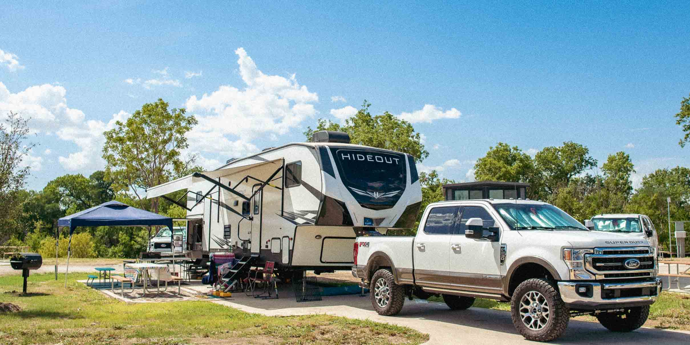 An RV campsite at Camp Fimfo Waco with concrete pad, and a charcoal grill