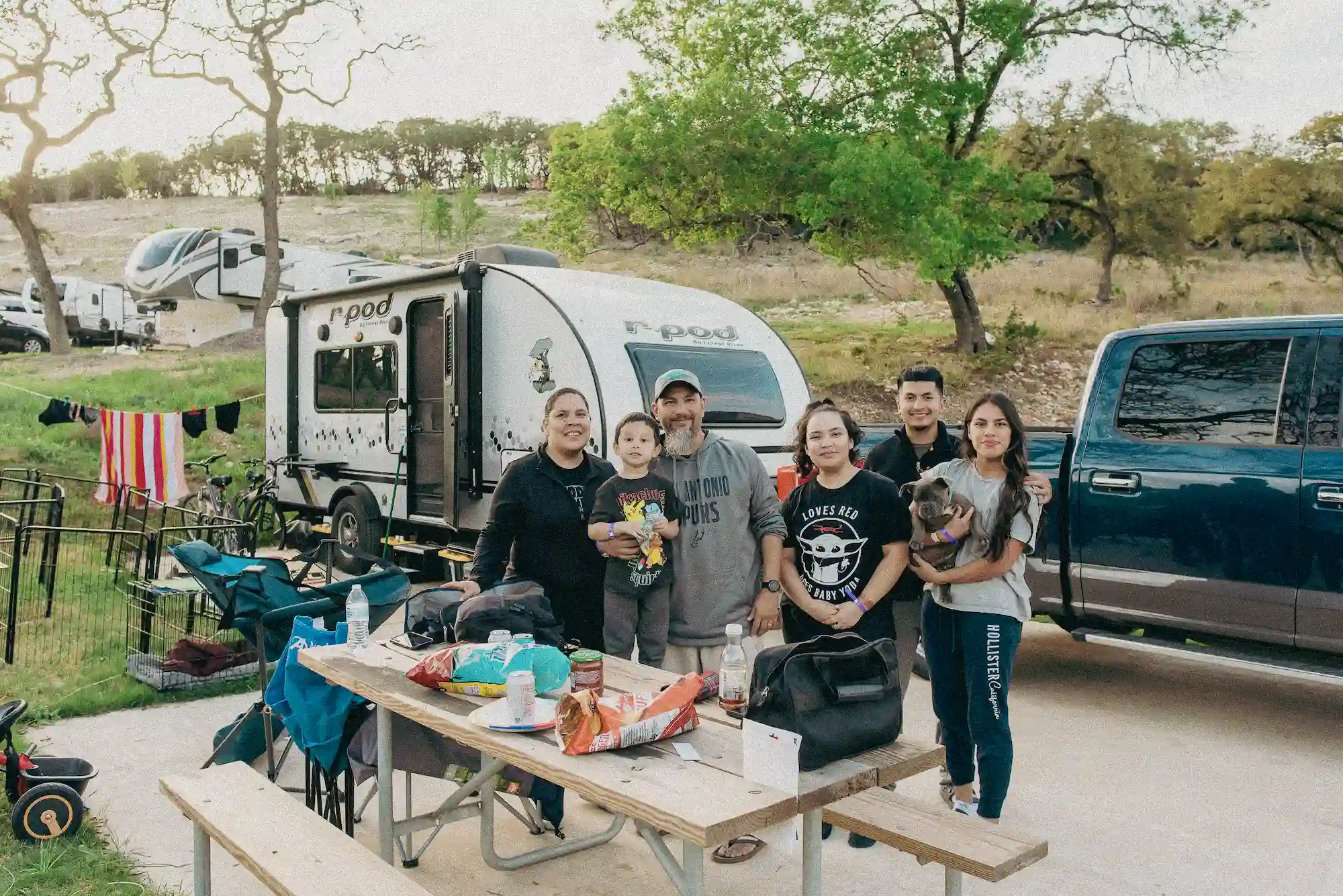 A family posing for a photo at their RV site at Camp Fimfo Texas Hill Country in New Braunfels, TX