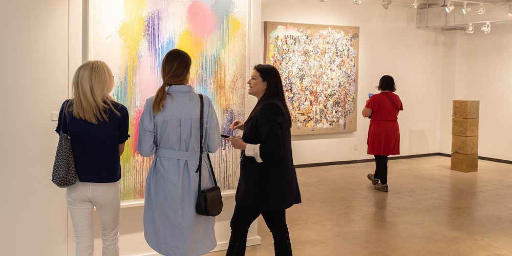 Women discussing an art piece at the Dallas Art Fair.