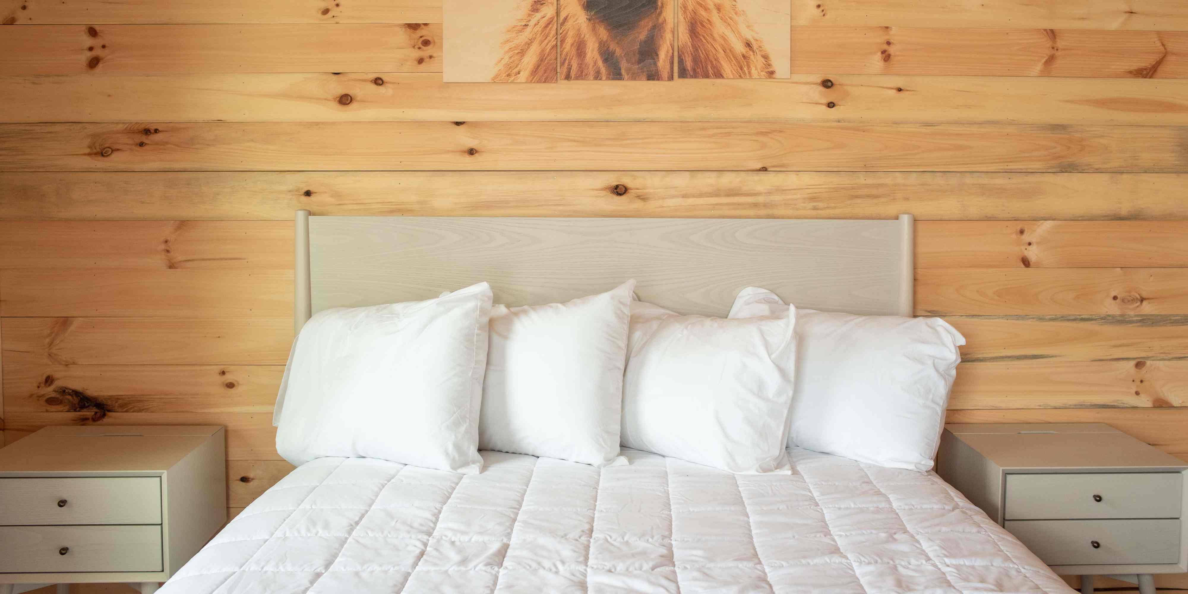 A queen bed in a private bedroom of the Mammoth Cabin at Camp Fimfo Waco