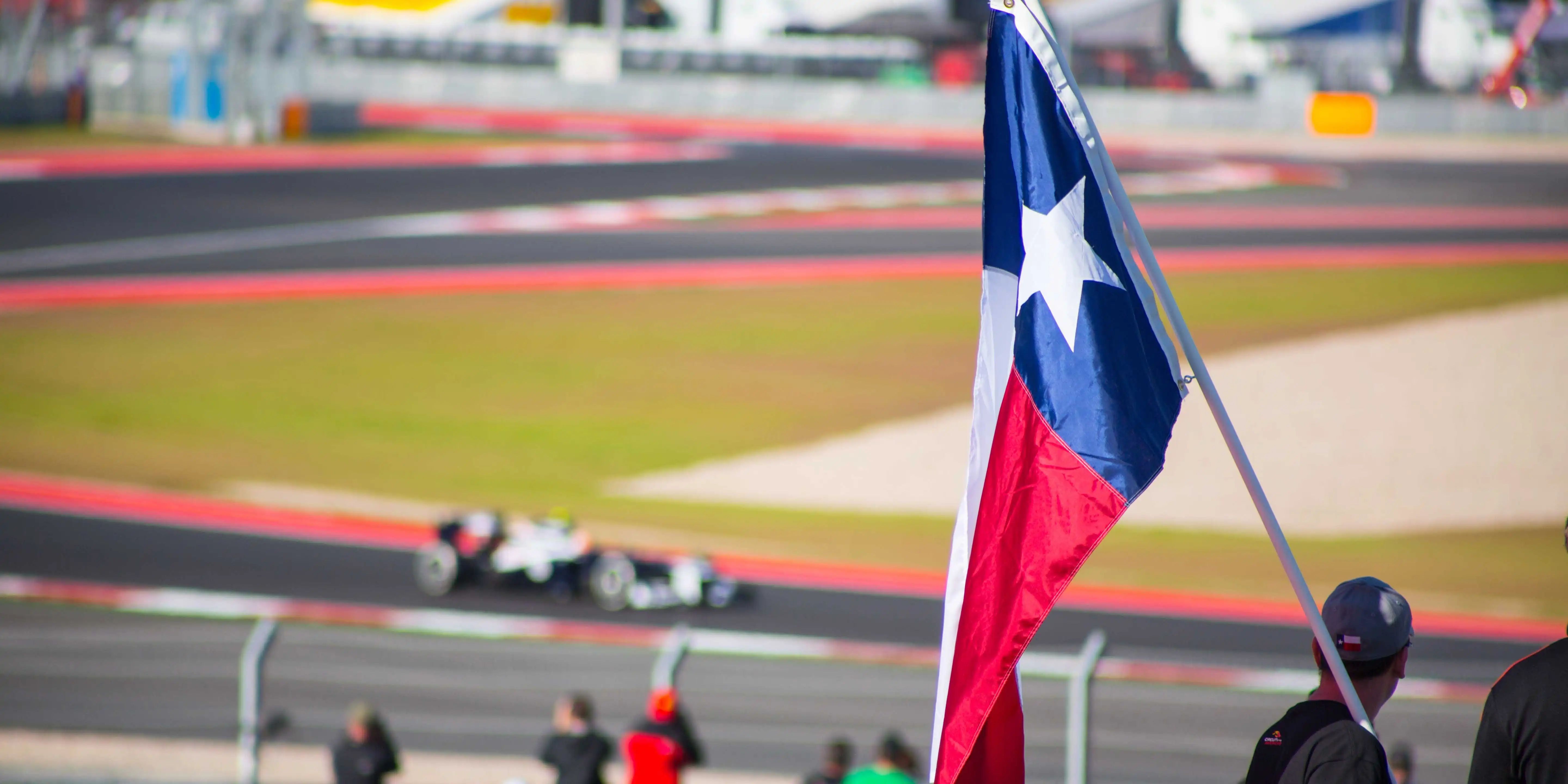 A fan waving a Texas flag at a Circuit of the Americas race in Austin, an awesome Austin event.