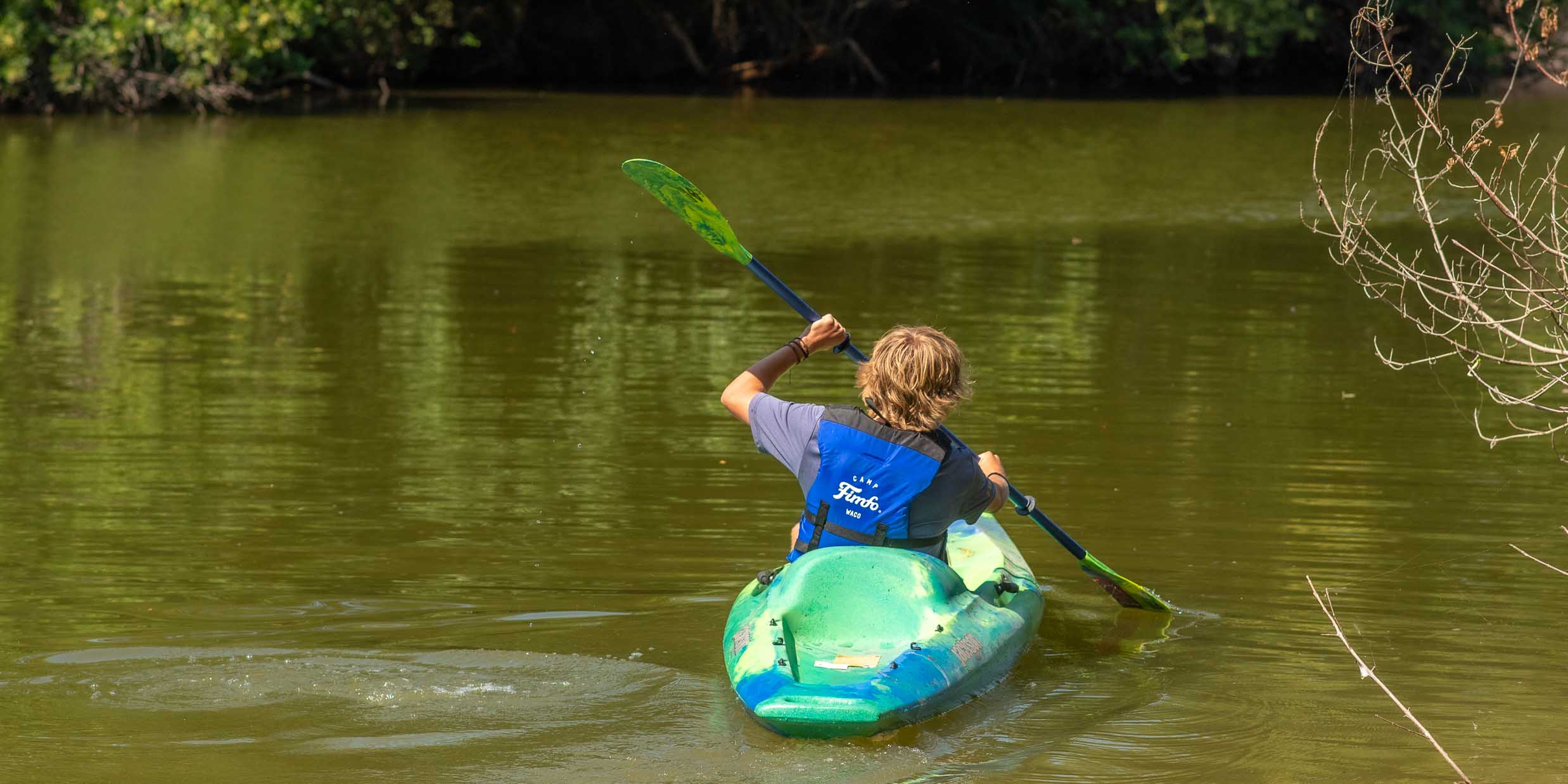 A guest kayaking on the Bosque River at Camp Fimfo Waco