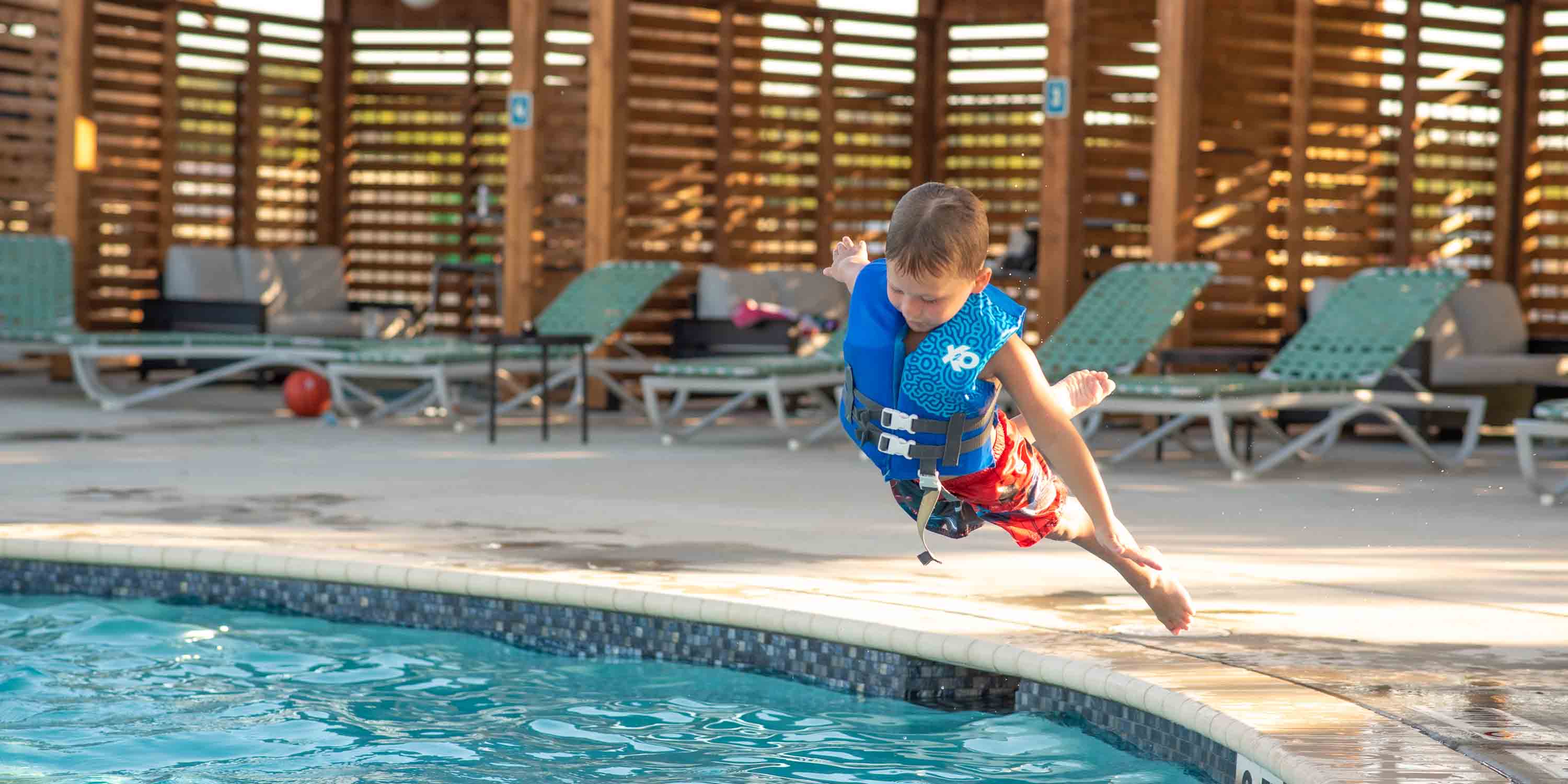 A child guest jumping into the pool at Camp Fimfo Waco