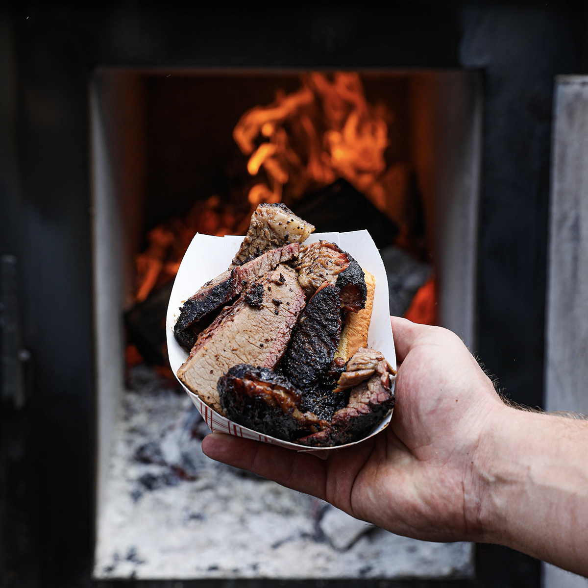 beef brisket being held in front of fire