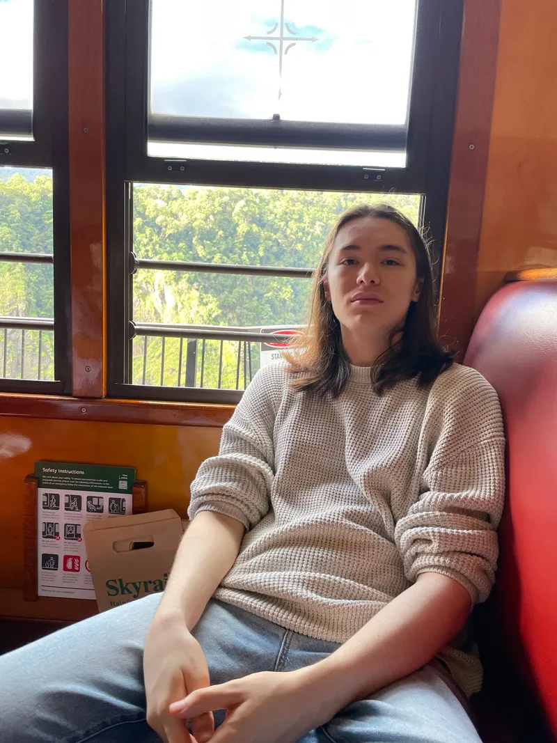 A teenager relaxing on the red seat by the window