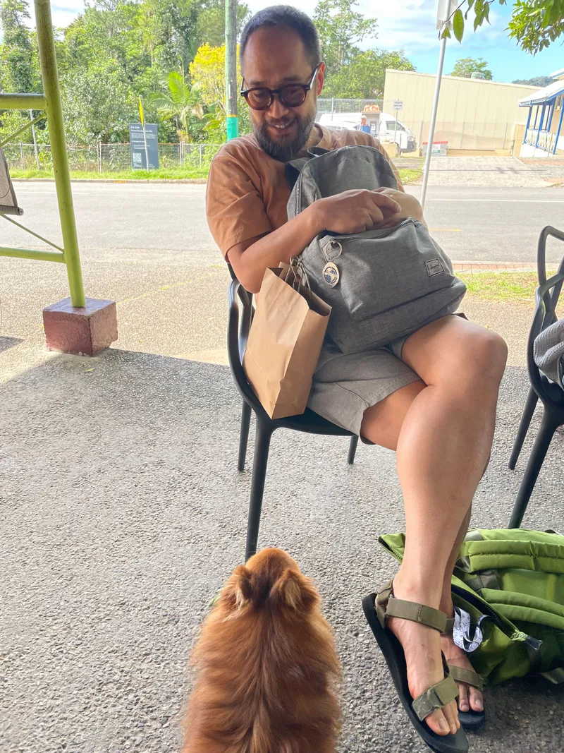 The man holding his backpack, the dog looking up at him
