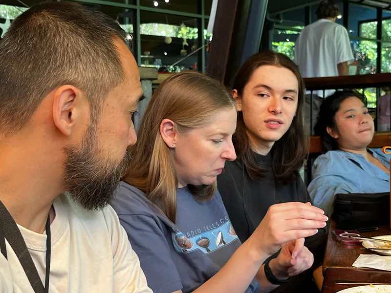 Four people at the lunch table, looking at something in a hand