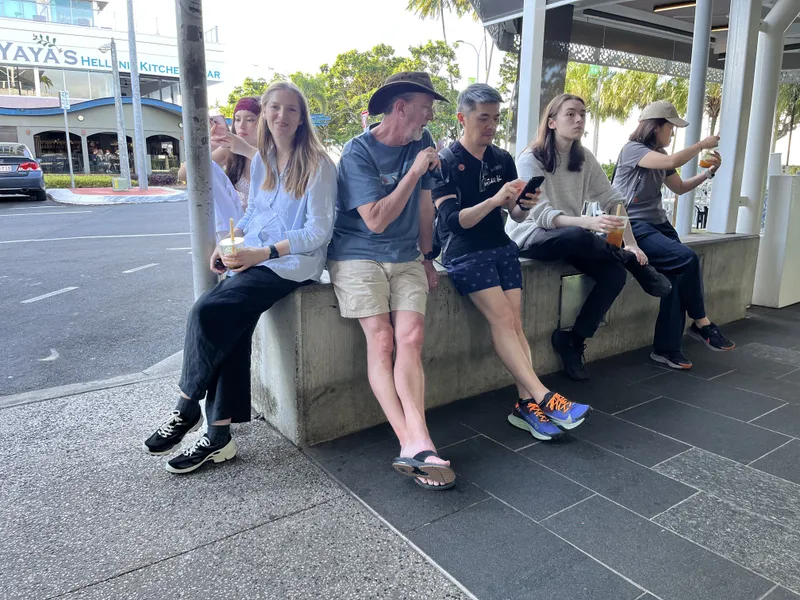 The group sitting on a low wall along the street with their bubble teas