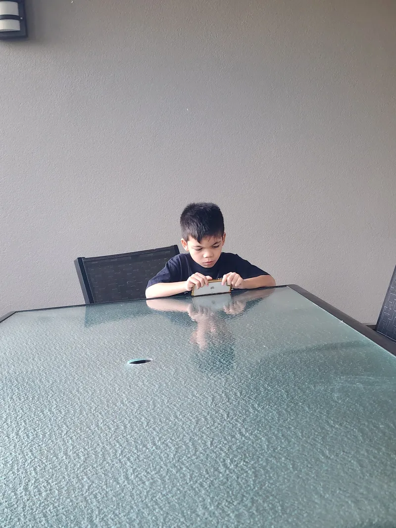 A boy at a glass table, looking at a tablet