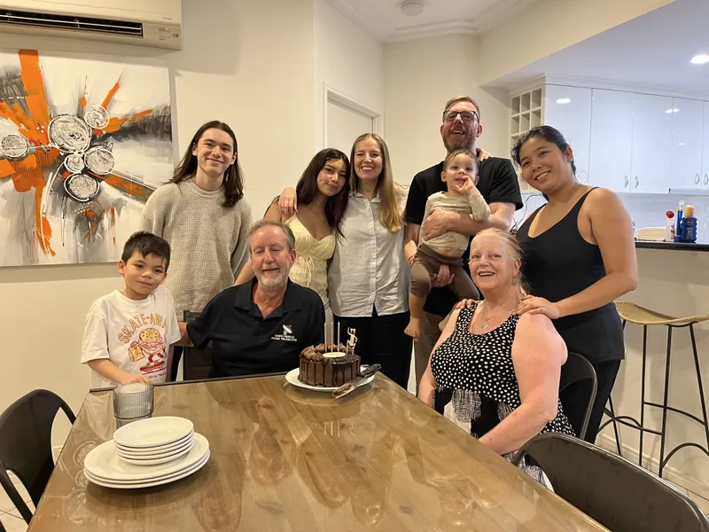 The whole group smiling around the table and the birthday cake