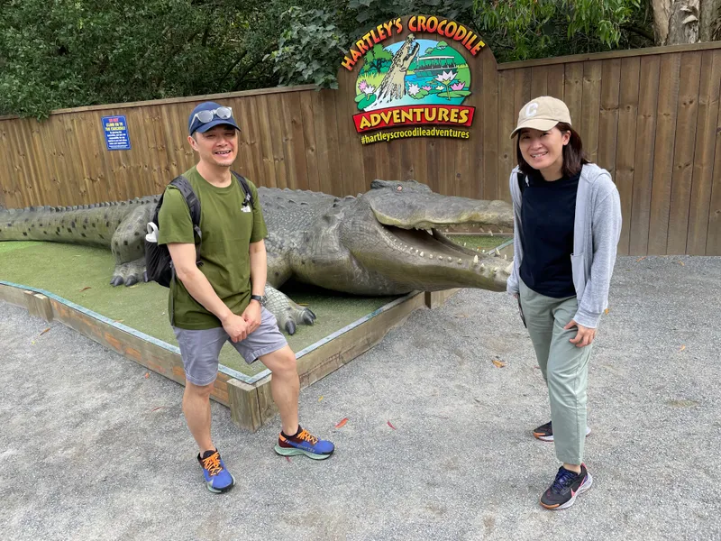 Two people standing by the giant crocodile statue under the Hartley's sign