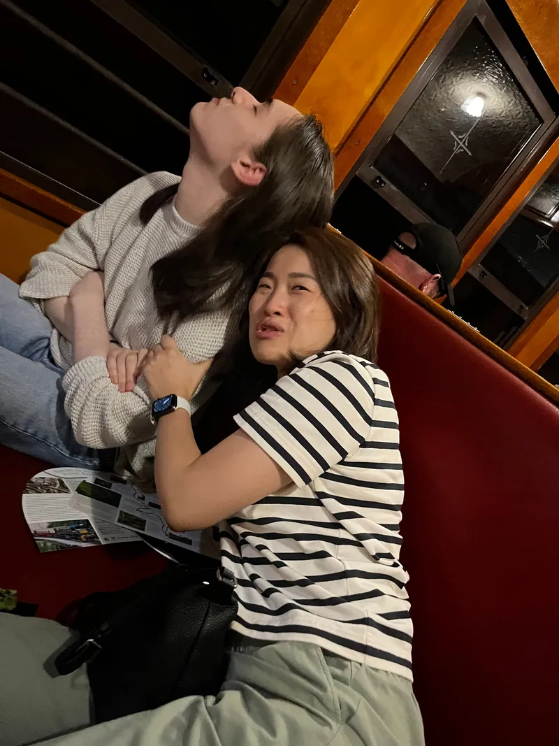 A woman hugging a teenager on the red seat