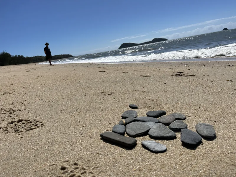 A circle of dark stones on the sand, with the islands behind