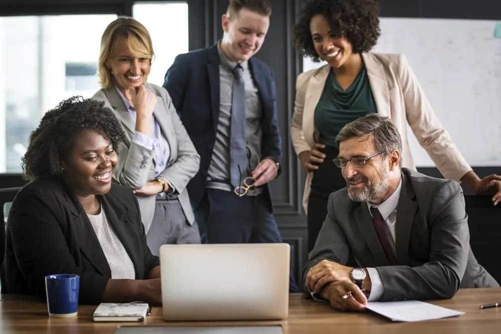 A team gathered around a laptop in an office, smiling