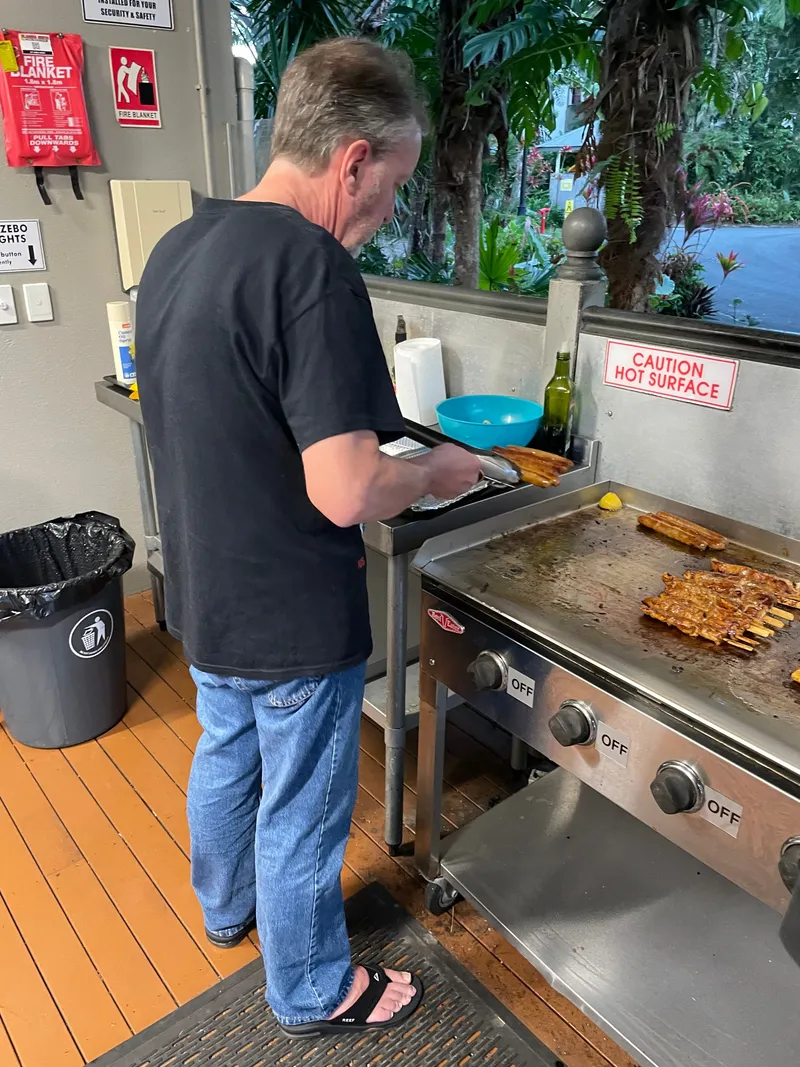 A man turning skewers on the flat-top