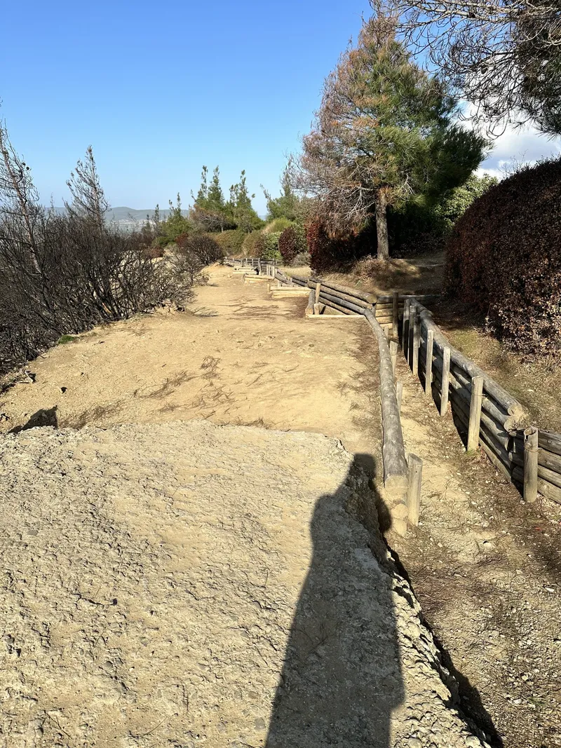 A dirt trench path beside a fence, with Chris’s shadow