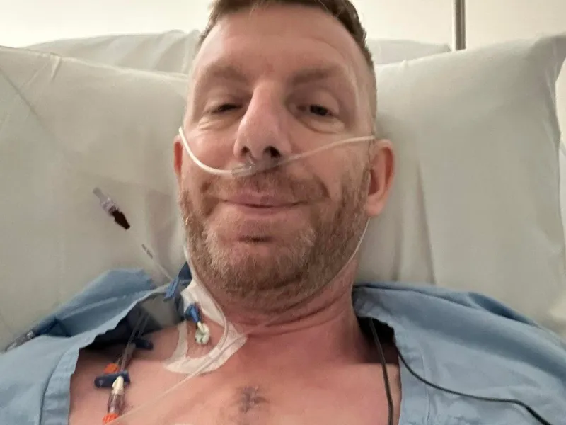 Chris smiling in a hospital bed after open-heart surgery