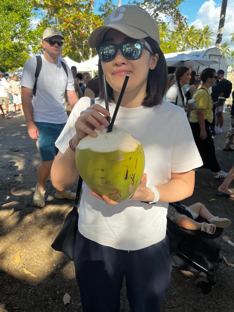 A woman holding a green coconut with a straw