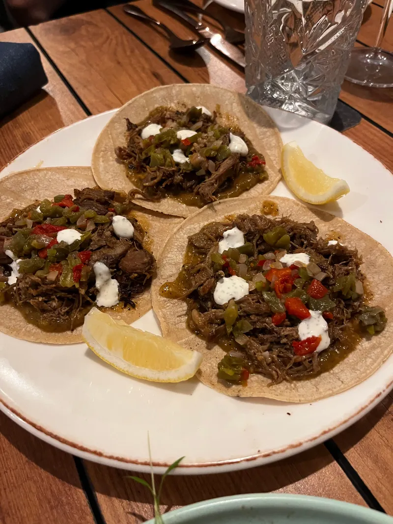 Three beef tacos with peppers and sour cream