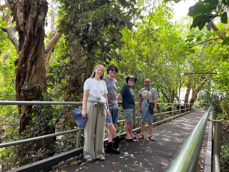 Four people on a boardwalk through the trees