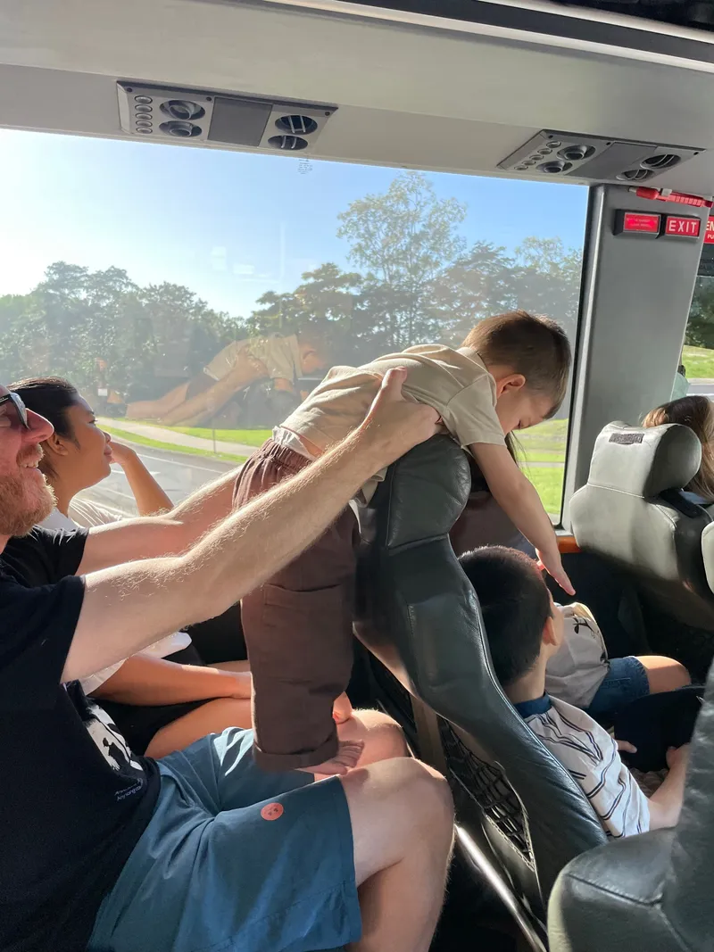 A man lifting a toddler up on the bus seats
