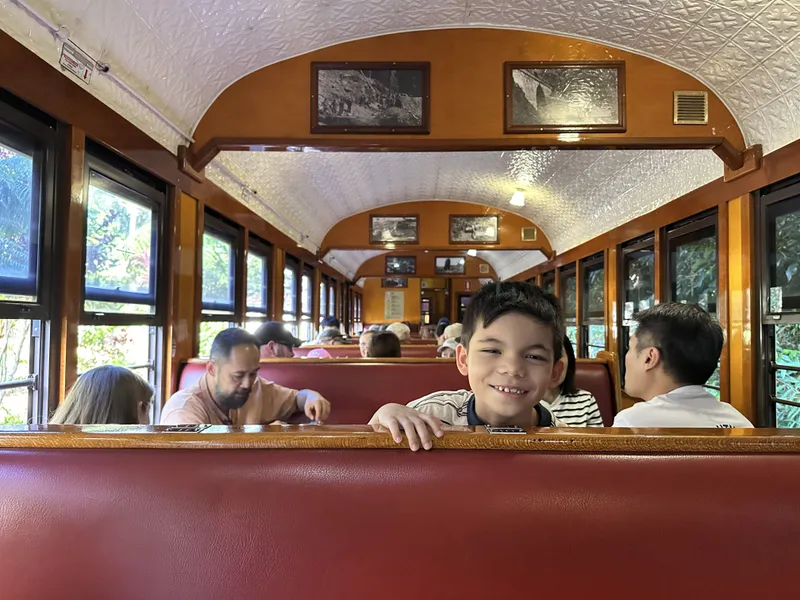 A boy grinning over the red seats in the heritage carriage