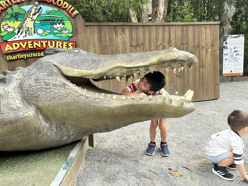 Two boys playing in the crocodile statue's open jaws