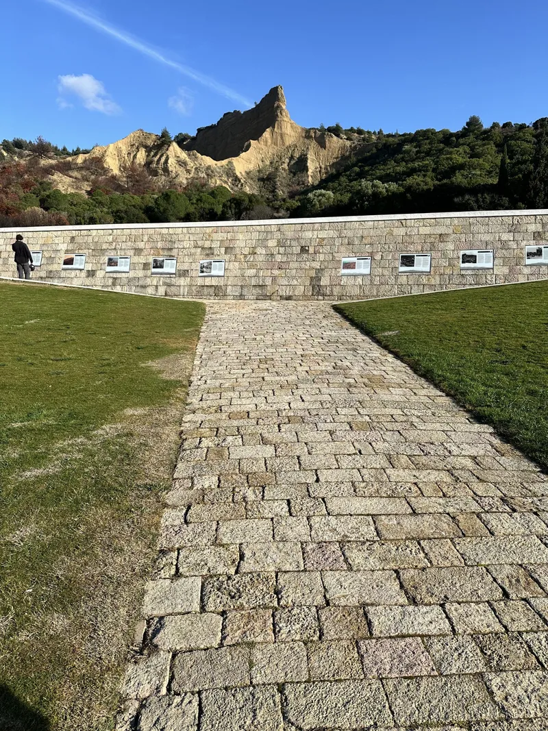 A stone path through a cemetery towards the Sphinx rock formation