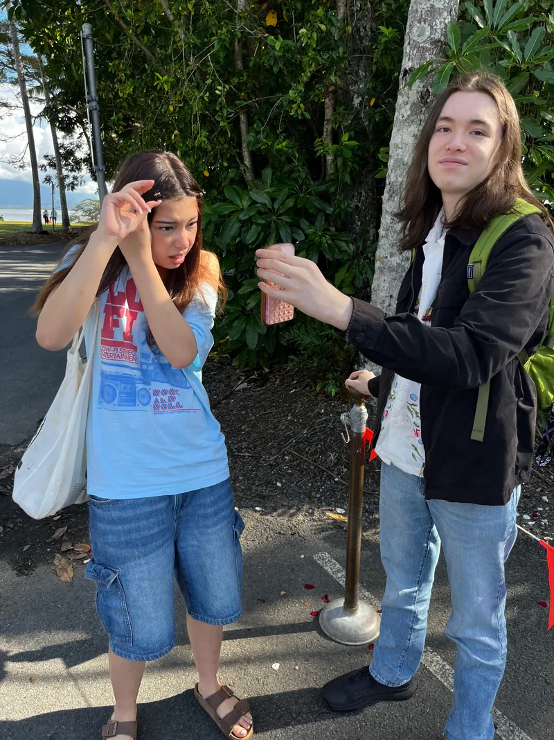 A girl shading her eyes and a teenager holding a phone by the water