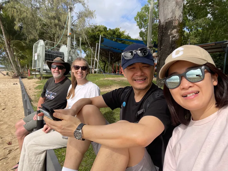 A selfie of four people sitting together above the beach