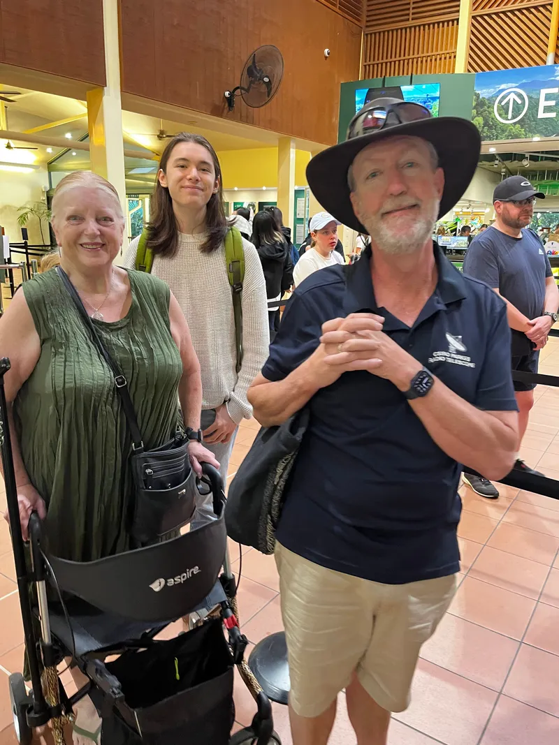 A woman with a walker, a teenager and a man in a bush hat in the queue