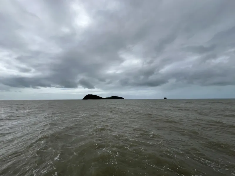 Grey sky over the sea, with an island on the horizon