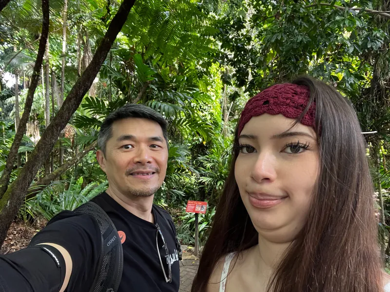 A selfie of a man and a girl in a headband in the rainforest garden