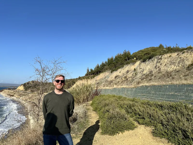Chris standing on the shore below the cliffs at Anzac Cove