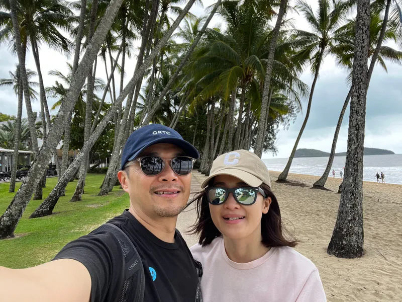 A selfie of two people under the palms along the foreshore