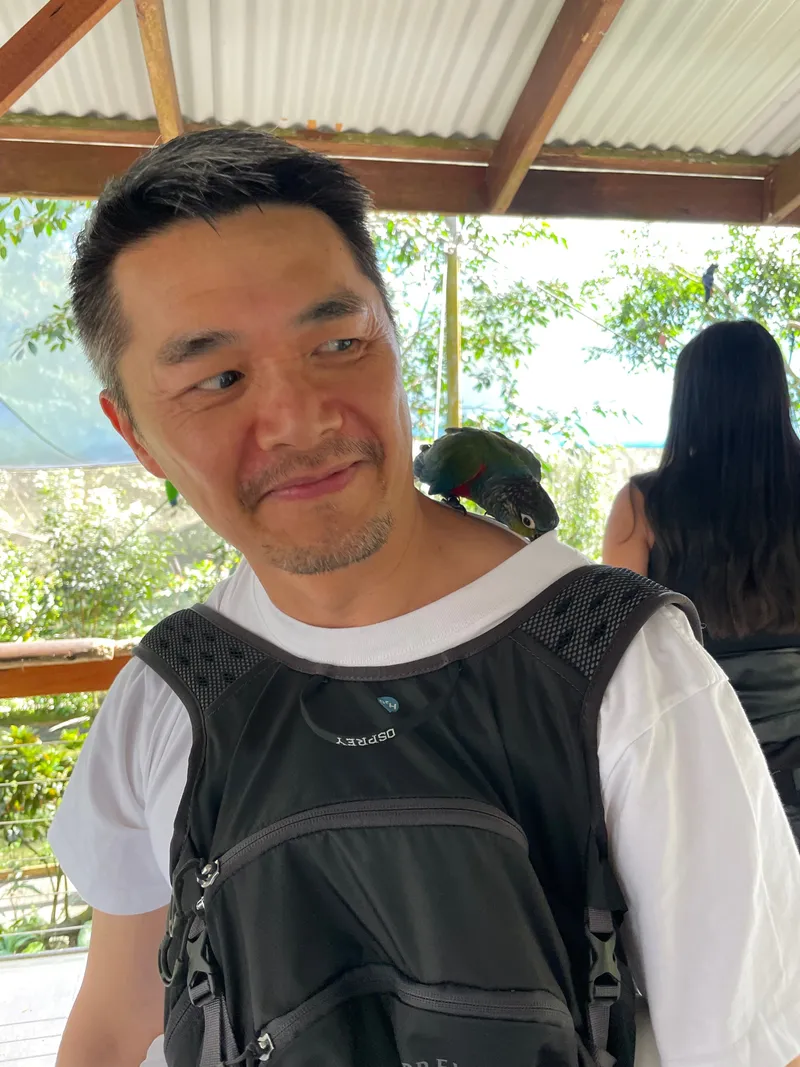 The man eyeing the parrot on his shoulder