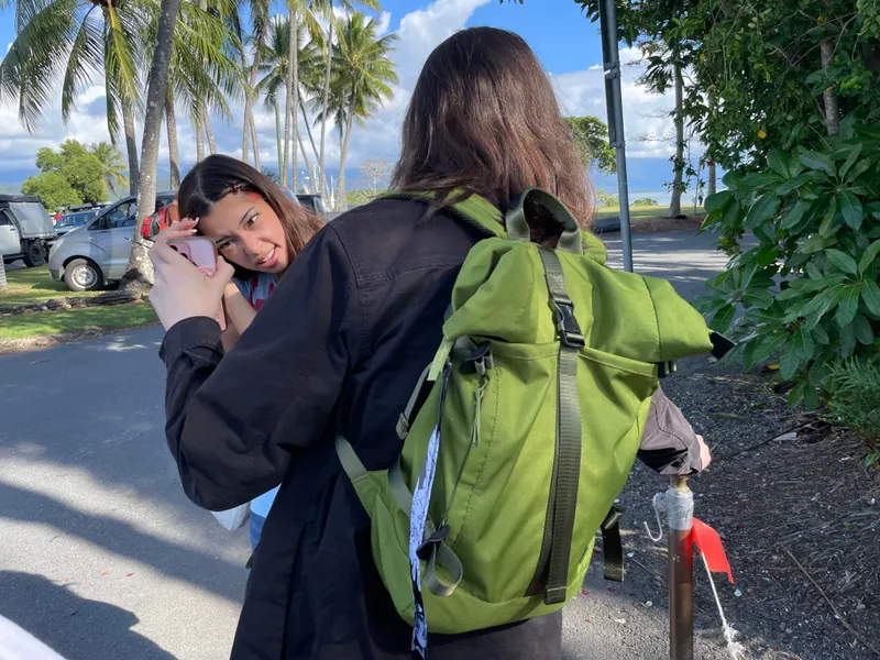 A girl being photographed beside a palm-lined road