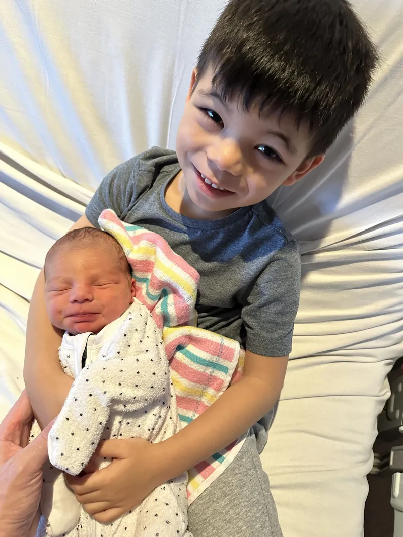 Jaxon smiling as he holds newborn Ethan