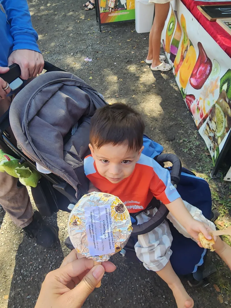A toddler in a stroller with a market treat
