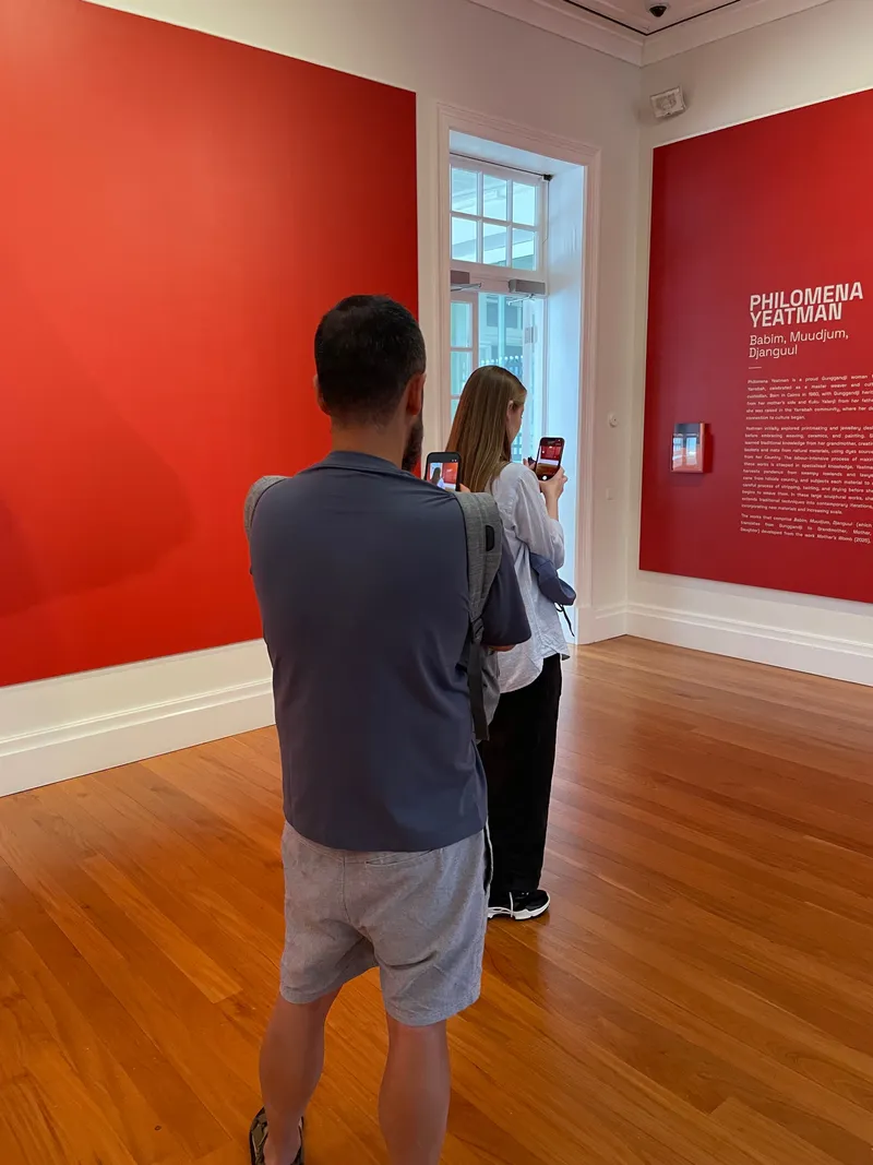 Two people reading the wall text in the red gallery room