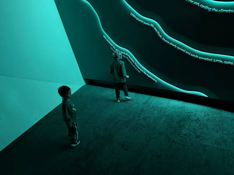 The boys exploring a glowing teal room with curved walls