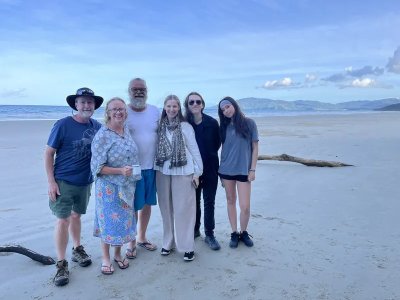 Six people on the wide sand, with a driftwood log behind them