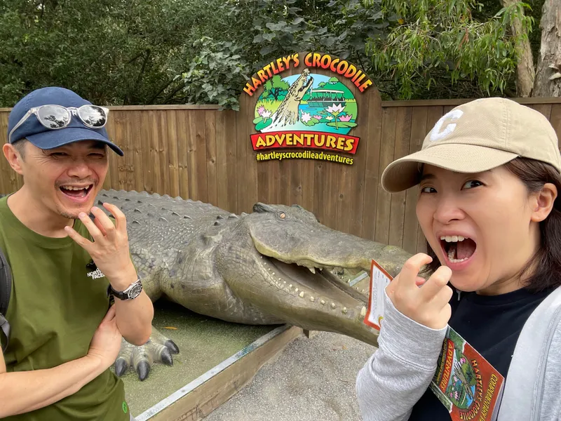 Two people pulling scared faces beside the crocodile statue