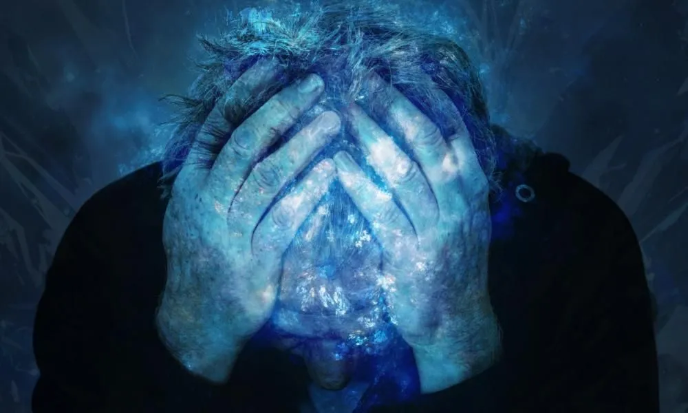 A man with his head in his hands under blue light