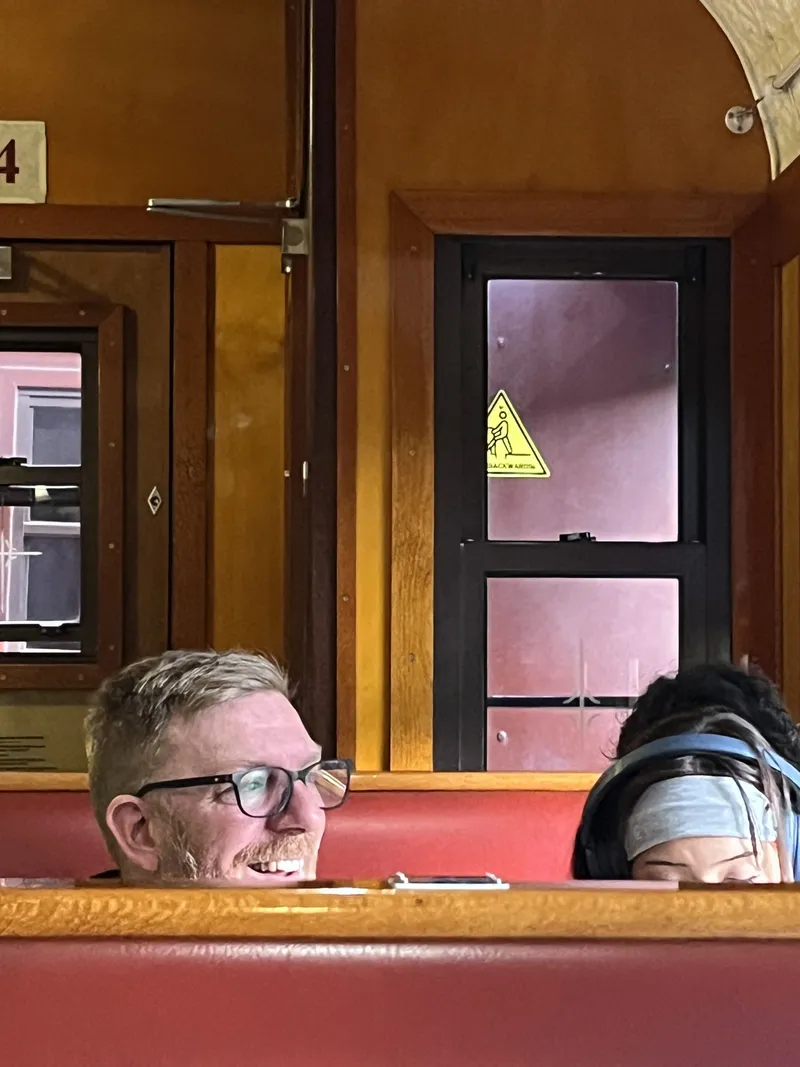 A man peeking over the seat back, with someone beside him