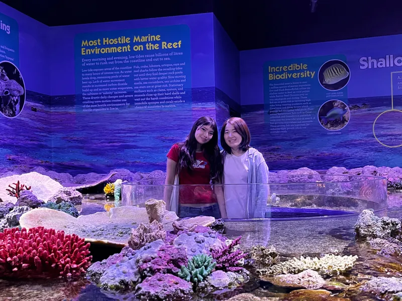 Two girls in front of a reef display about the most hostile marine environment on the reef