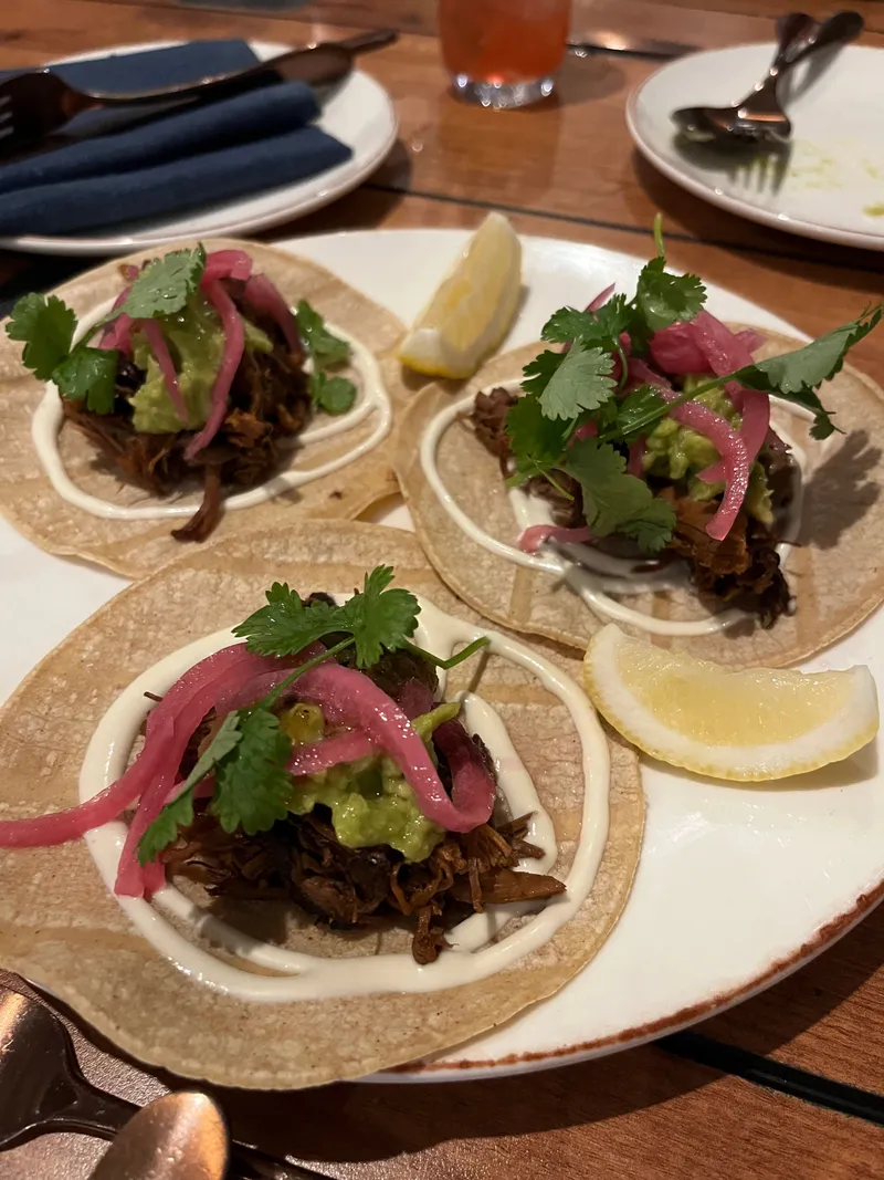 Three tacos with pickled onion, guacamole and coriander