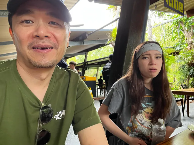 A selfie of a man at the cafe, with a girl in a headband beside him