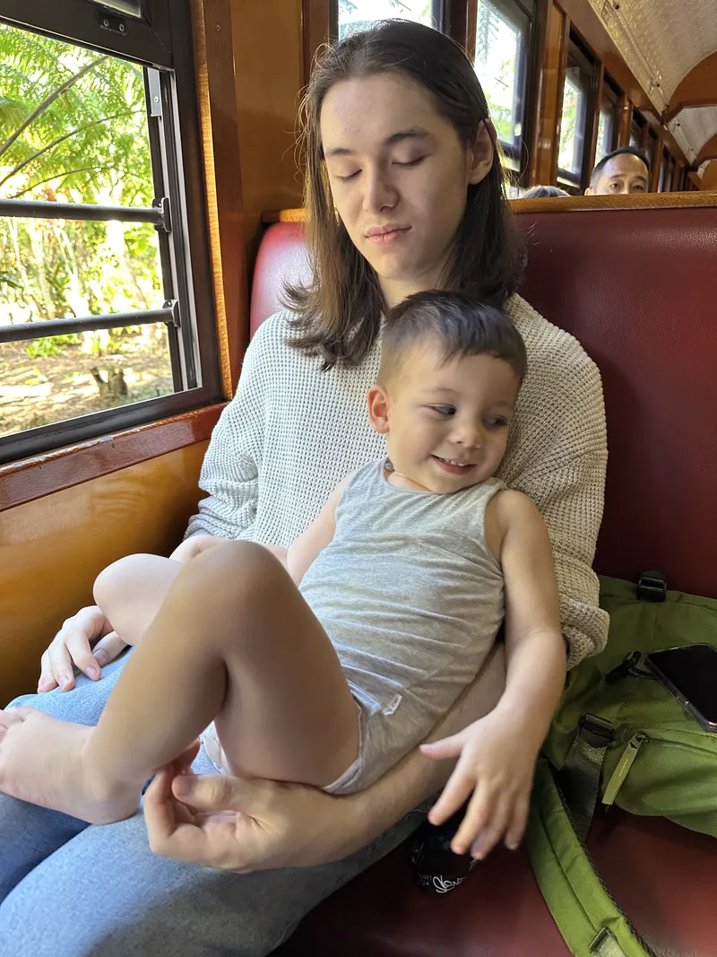 The toddler smiling on the teenager's lap