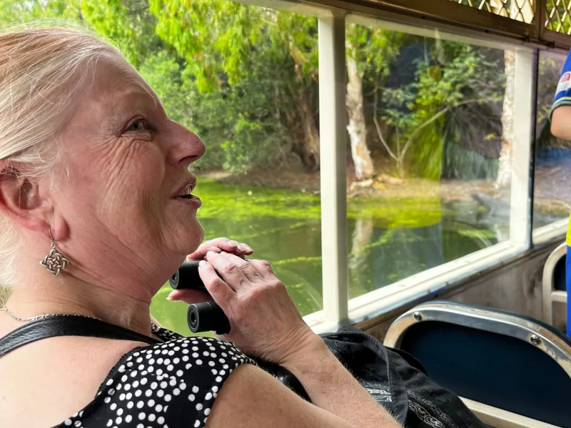 An older woman on the boat, smiling as she watches the crocodiles